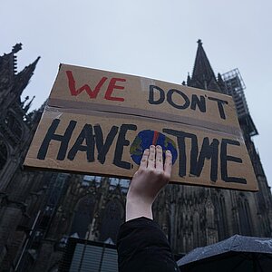 Poster raised by hand, saying "We don't have time."